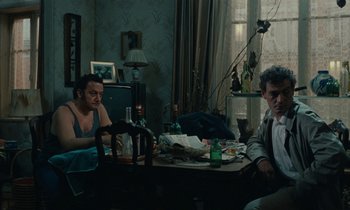 Movie still from “So Long, Stooge” (1983), directed by Claude Berri – Two men sitting at a table in front of a window; Wide shot, High angle