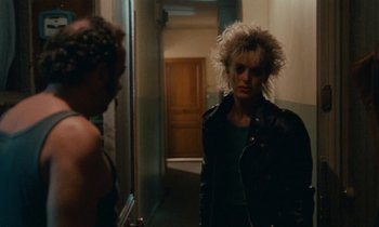 Movie still from “So Long, Stooge” (1983), directed by Claude Berri – A woman in a leather jacket standing next to a man; Medium shot, Over the shoulder angle