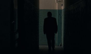 Movie still from “So Long, Stooge” (1983), directed by Claude Berri – A man is walking in a dark hallway; Wide shot, Low angle