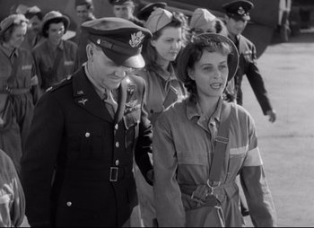Movie still from “So Proudly We Hail” (1990), directed by Lionel Chetwynd – A group of people in uniform walking down a street; Medium shot, Low angle