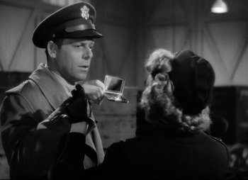 Movie still from “So Proudly We Hail” (1990), directed by Lionel Chetwynd – An old photo of a man in uniform holding a camera; Close Up shot, Low angle