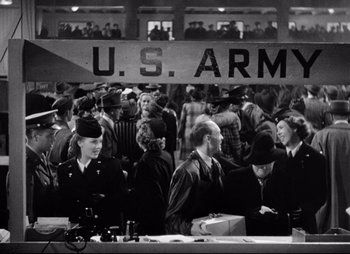 Movie still from “So Proudly We Hail” (1990), directed by Lionel Chetwynd – A group of people standing in a room; Wide shot, Low angle