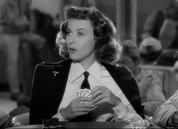 Movie still from “So Proudly We Hail” (1990), directed by Lionel Chetwynd – A black and white photo of a woman holding a deck of playing cards; Close Up shot, Over the shoulder angle