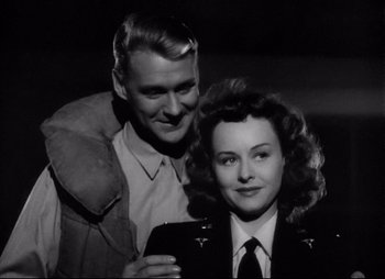 Movie still from “So Proudly We Hail” (1990), directed by Lionel Chetwynd – A man and a woman posing for a picture in black and white; Medium shot, Low angle