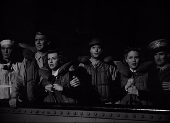 Movie still from “So Proudly We Hail” (1990), directed by Lionel Chetwynd – A black and white photo of a group of men and women; Medium shot, Low angle