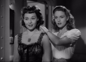 Movie still from “So Proudly We Hail” (1990), directed by Lionel Chetwynd – Two women are standing next to each other in a room; Medium shot, High angle