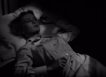 Movie still from “So Proudly We Hail” (1990), directed by Lionel Chetwynd – A black and white photo of a woman laying on a bed; Medium shot, High angle