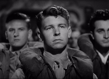 Movie still from “So Proudly We Hail” (1990), directed by Lionel Chetwynd – Black and white photograph of a young man in a military uniform; Close Up shot, Low angle