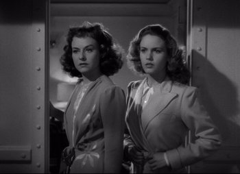 Movie still from “So Proudly We Hail” (1990), directed by Lionel Chetwynd – A black - and - white photo of two women standing next to each other in front of a mirror; Close Up shot, Low angle