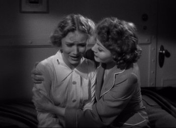 Movie still from “So Proudly We Hail” (1990), directed by Lionel Chetwynd – Two women are hugging in a room; Medium shot, High angle