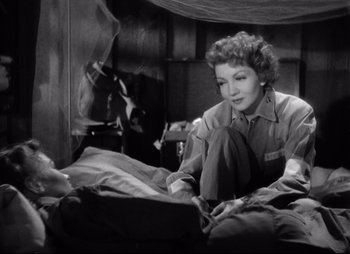 Movie still from “So Proudly We Hail” (1990), directed by Lionel Chetwynd – A woman sitting on top of a bed next to a man; Medium shot, High angle