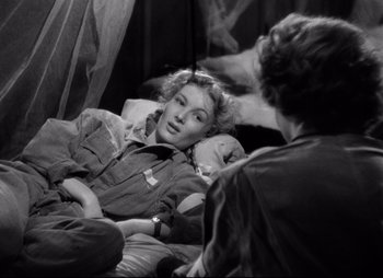 Movie still from “So Proudly We Hail” (1990), directed by Lionel Chetwynd – A black - and - white photo of a woman laying on a bed; Medium shot, High angle