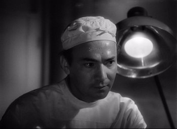 Movie still from “So Proudly We Hail” (1990), directed by Lionel Chetwynd – Black and white photograph of a man wearing a hat; Close Up shot, Low angle