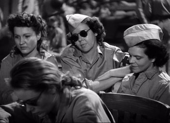 Movie still from “So Proudly We Hail” (1990), directed by Lionel Chetwynd – A black and white photo of a group of women sitting together; Medium shot, Low angle