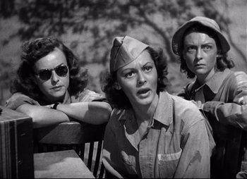 Movie still from “So Proudly We Hail” (1990), directed by Lionel Chetwynd – A group of women sitting next to each other on a park bench; Medium shot, Low angle