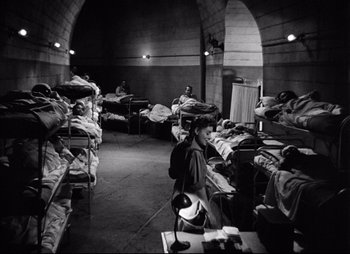 Movie still from “So Proudly We Hail” (1990), directed by Lionel Chetwynd – A group of people in a room with beds; Wide shot, High angle