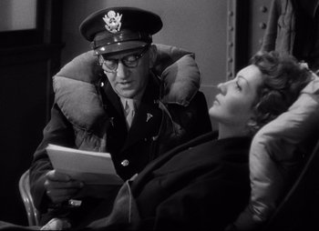 Movie still from “So Proudly We Hail” (1990), directed by Lionel Chetwynd – An old photo of a man and a woman looking at a piece of paper; Medium shot, Over the shoulder angle