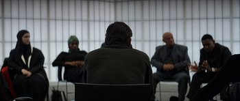 Movie still from “Solaris” (2002), directed by Steven Soderbergh – A man sitting in front of two other men in a room; Medium shot, Over the shoulder angle