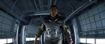 Movie still from “Solaris” (2002), directed by Steven Soderbergh – A man in a spacesuit is standing in an airplane; Medium shot, Low angle