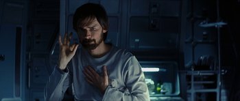 Movie still from “Solaris” (2002), directed by Steven Soderbergh – A man standing in a kitchen holding his hands to his chest; Close Up shot, Over the shoulder angle