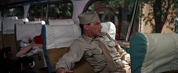 Movie still from “Some Came Running” (1958), directed by Vincente Minnelli – A man sitting in a car wearing a hat and a tie; Medium shot, Over the shoulder angle
