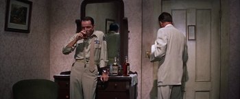 Movie still from “Some Came Running” (1958), directed by Vincente Minnelli – A man in a suit and tie standing in front of a mirror; Medium shot, Low angle