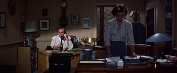 Movie still from “Some Came Running” (1958), directed by Vincente Minnelli – A man and a woman are sitting at a desk; Medium shot, High angle