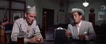 Movie still from “Some Came Running” (1958), directed by Vincente Minnelli – A couple of men sitting at a table with a drink; Medium shot, Low angle