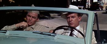 Movie still from “Some Came Running” (1958), directed by Vincente Minnelli – A man driving a car while another man looks on; Medium shot, Over the shoulder angle