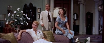 Movie still from “Some Came Running” (1958), directed by Vincente Minnelli – Two women and a man sitting on a couch in a living room; Medium shot, Low angle