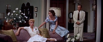 Movie still from “Some Came Running” (1958), directed by Vincente Minnelli – Two women sitting on a couch in front of a lamp; Medium shot, Low angle