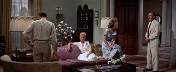 Movie still from “Some Came Running” (1958), directed by Vincente Minnelli – A group of women sitting on a couch in a living room; Wide shot, High angle