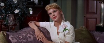Movie still from “Some Came Running” (1958), directed by Vincente Minnelli – A woman sitting on top of a couch wearing a white dress; Close Up shot, Low angle
