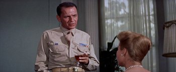 Movie still from “Some Came Running” (1958), directed by Vincente Minnelli – A man in a military uniform holding a glass of beer; Medium shot, Over the shoulder angle