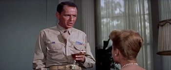 Movie still from “Some Came Running” (1958), directed by Vincente Minnelli – A man in a military uniform holding a glass of wine; Medium shot, Over the shoulder angle