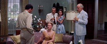 Movie still from “Some Came Running” (1958), directed by Vincente Minnelli – A group of people standing in a living room next to each other; Medium shot, Low angle