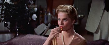 Movie still from “Some Came Running” (1958), directed by Vincente Minnelli – A beautiful woman holding a glass of wine while wearing a pearl necklace; Close Up shot, Low angle