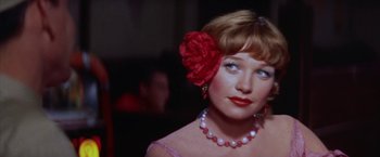 Movie still from “Some Came Running” (1958), directed by Vincente Minnelli – A person wearing a necklace and a flower in her hair; Close Up shot, Over the shoulder angle