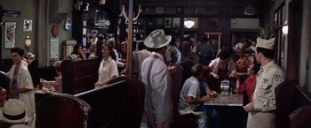 Movie still from “Some Came Running” (1958), directed by Vincente Minnelli – A group of people sitting at tables in a restaurant; Wide shot, High angle