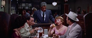 Movie still from “Some Came Running” (1958), directed by Vincente Minnelli – A group of people sitting at a table eating food; Medium shot, Over the shoulder angle