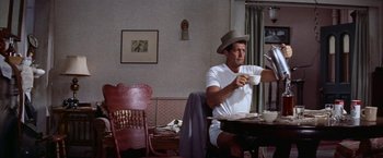 Movie still from “Some Came Running” (1958), directed by Vincente Minnelli – A man sitting at a table with a cup of coffee; Medium shot, Low angle