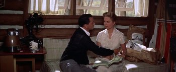 Movie still from “Some Came Running” (1958), directed by Vincente Minnelli – A man and a woman sitting on a couch in front of a window; Medium shot, High angle