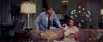 Movie still from “Some Came Running” (1958), directed by Vincente Minnelli – A man and a woman sitting on top of a purple couch; Medium shot, High angle