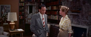 Movie still from “Some Came Running” (1958), directed by Vincente Minnelli – A man and a woman standing in front of a book shelf; Medium shot, Low angle