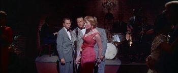 Movie still from “Some Came Running” (1958), directed by Vincente Minnelli – A group of men and a woman singing in front of a microphone; Medium shot, Low angle