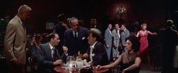 Movie still from “Some Came Running” (1958), directed by Vincente Minnelli – A group of men sitting at a table in front of a crowd; Medium shot, Low angle