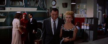 Movie still from “Some Came Running” (1958), directed by Vincente Minnelli – A man and a woman standing next to each other in front of a bus; Medium shot, Over the shoulder angle