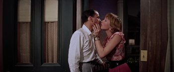 Movie still from “Some Came Running” (1958), directed by Vincente Minnelli – A man and a woman kissing in front of a building; Medium shot, High angle