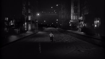 Movie still from “Somebody Up There Likes Me” (1956), directed by Robert Wise – A man walking down a street at night; Extreme Wide shot, High angle
