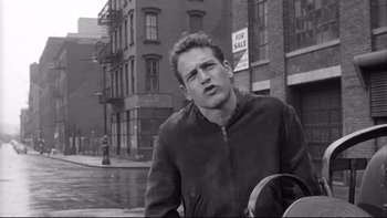 Movie still from “Somebody Up There Likes Me” (1956), directed by Robert Wise – Black and white photograph of a man in a city street; Close Up shot, Over the shoulder angle